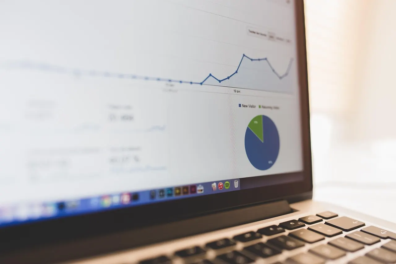 Laptop screen showing an email marketing dashboard with a line chart and pie chart on a desk